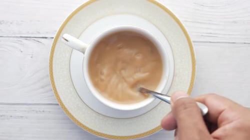 Person Hand Stirring Tea with Spoon