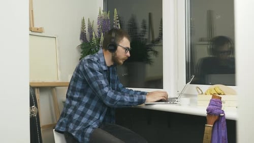 Young Adult Typing at Laptop in Home Office