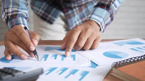 Mão de homem com caneta analisando gráfico de barras em papel