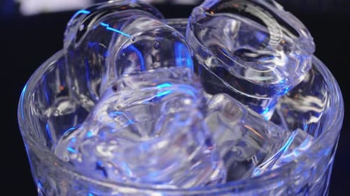Bartender Adds Ice Cubes to the Glass in Slow Motion Making the Cocktail at the Bar Counter Blue