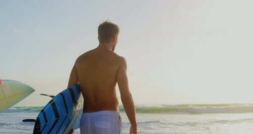 Couple standing with surfboard on beach in the sunshine