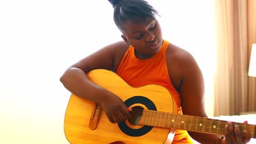 Woman Plays Acoustic Guitar in a Bedroom
