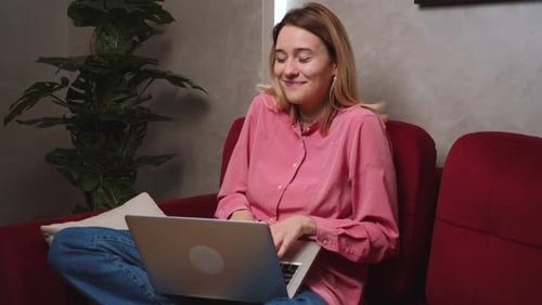 Young Woman Using Laptop on Couch Indoors