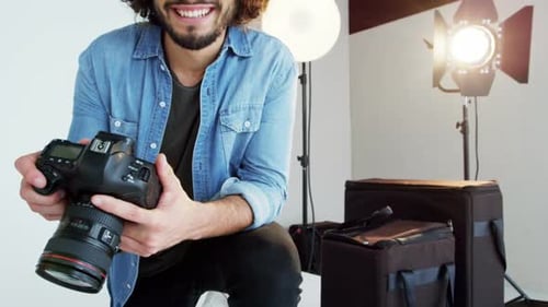 Smiling Photographer Holding Camera in a Bright Studio
