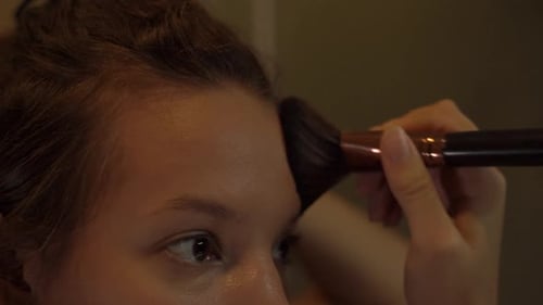 Young Adult Applying Makeup with Brush Indoors