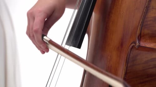 Woman Is Playing the Cello on White Background. Close Up of Bow and Strings. Steadicam Shot