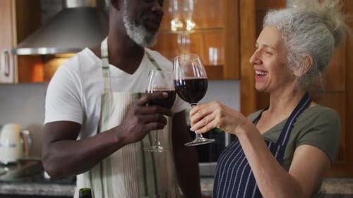 Smiling Couple Toasts with Red Wine in Kitchen