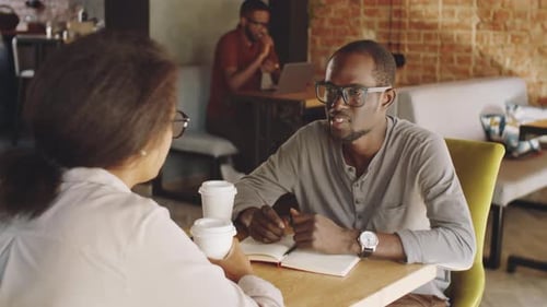 Afro-American Colleagues Talking on Coffee Break in Cafe