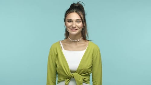 Süßes und bescheidenes Mädchen, das die Augenbrauen hochzieht und lächelt, mit den Schultern zuckt, schüchtern, Komplimente erhalten oder