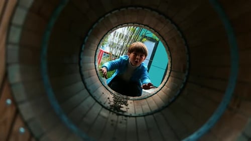 A Little Boy Playing on the Playground - Crawling Through the Tube