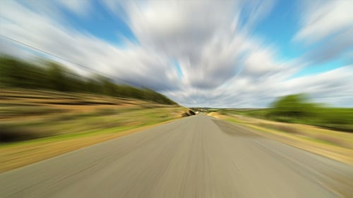Fast Driving Car on the Road in Green Fields