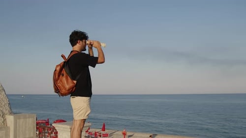 Junge blickt mit einem Laken wie ein Fernglas auf das Meer am Horizont