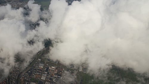 Airplane Flying over City and Clouds