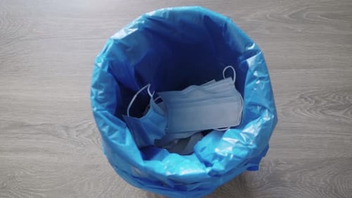 Face Masks and Gloves Discarded in Trash Can
