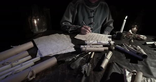 Medieval Scribe Writes by Candlelight at Dark Table