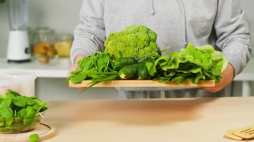 Woman Preparing Fresh Green Vegetables on Cutting Board