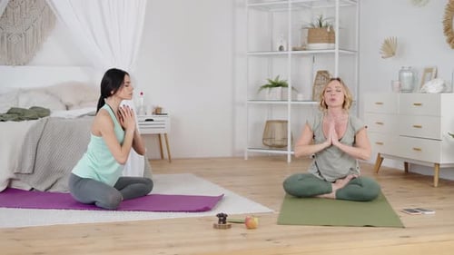 Two Women Practicing Yoga and Stretching Indoors