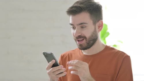Man Celebrates Good News on Smartphone