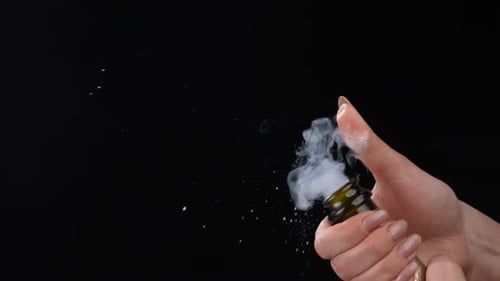Female Hand Uncorking Bottle of Champagne on Black Background