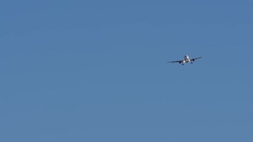 Commercial Airplane Landing in Blue Sky on Sunny Day