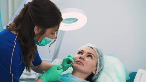 Kosmetikerin mit Maske injiziert dem Kunden Gesichtsfüller