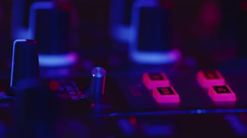 Nahaufnahme eines professionellen DJs, der den Fader auf der digitalen Musikkonsole in rosa Neonlicht im Nachtclub einstellt