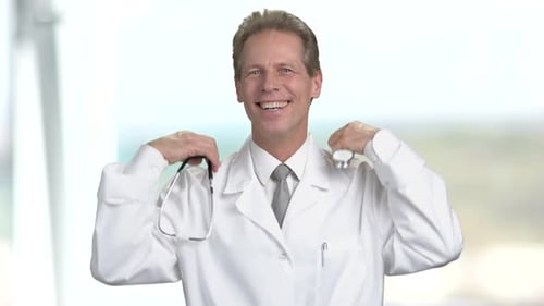 Smiling Doctor Putting on Stethoscope Indoors