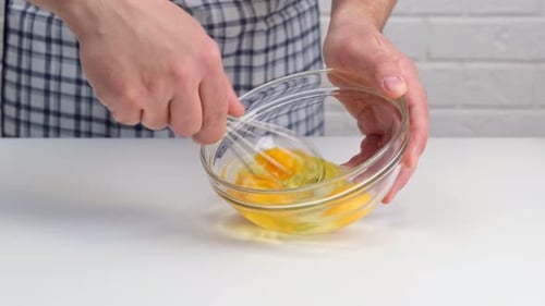 Man Whisking Eggs in a Glass Bowl