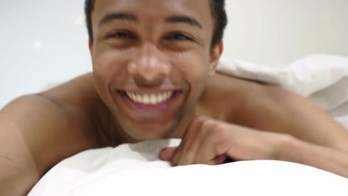 Pouce levé par un homme africain heureux allongé dans son lit sur le ventre