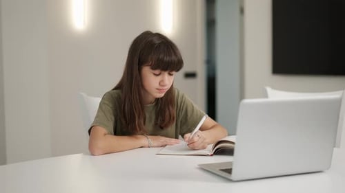 Girl Studying at Table with Laptop and Notebook