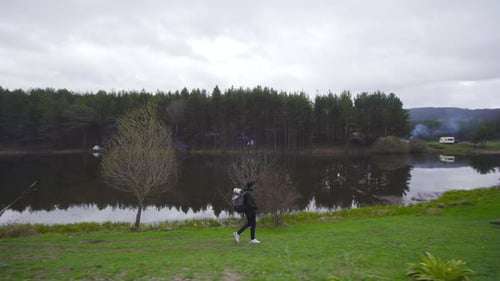 Hiker with Backpack Walking by Calm Lake