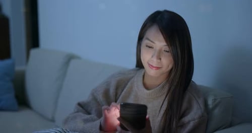 Woman Using Smartphone on Couch at Night