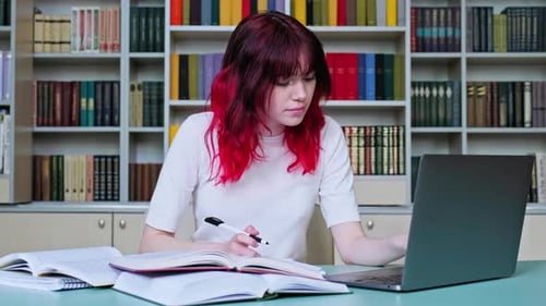 High School Student Girl Studying in School Library Using Books and Laptop
