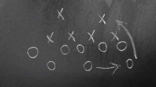 Coach using chalkboard for football match tactics.