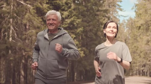 Happy Mature Couple Jogging in Forest on Sunny Day