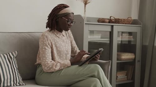 Woman Relaxes on Couch Using Tablet at Home
