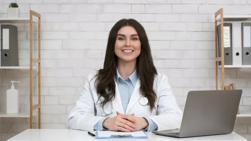 Smiling Female Therapist Talking Sitting At Laptop In Office