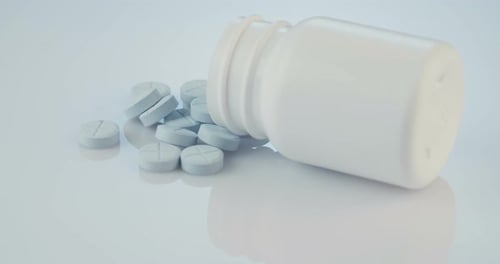 Blue Pills Spill from White Pill Bottle