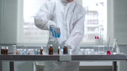Wissenschaftler für schützende Arbeitskleidung und Handschuhe arbeiten im Labor mit Chemikalien