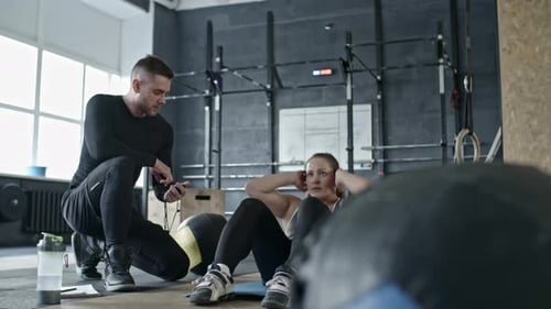 Personal Coach Controlling Woman Doing Abs Crunches