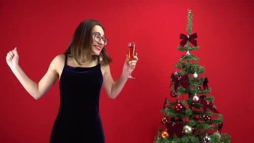 Woman Celebrates Christmas with Champagne by Tree