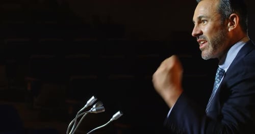 Caucasian businessman speaking at podium on stage in auditorium 4k
