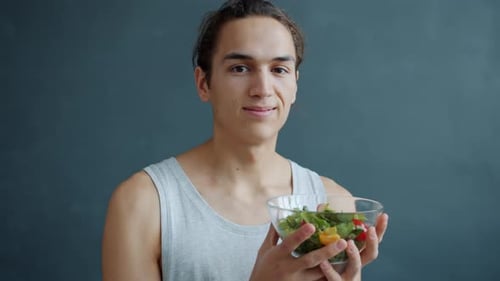 Young Man Holds Bowl of Fresh Salad