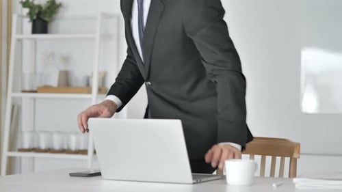 Empresario dejando la oficina después de cerrar portátil en el trabajo