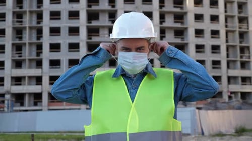 Construction Worker Puts on Face Mask for Safety