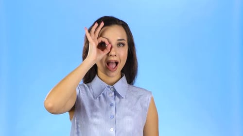 Smiling Woman Making OK Hand Gesture on Blue Background