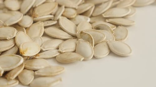 Close-up of raw organic pepitas slow pan 4K 2160p 30fps UltraHD footage - Pile of pumpkin seed on wh