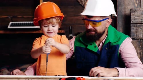 Construction of Father and Son in the Garage. Little Son Helping His Father with Building Work