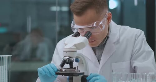 Man Looking Through Microscope in Modern Laboratory