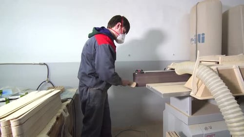 Man Shaping Wood with Sanding Machine in Factory